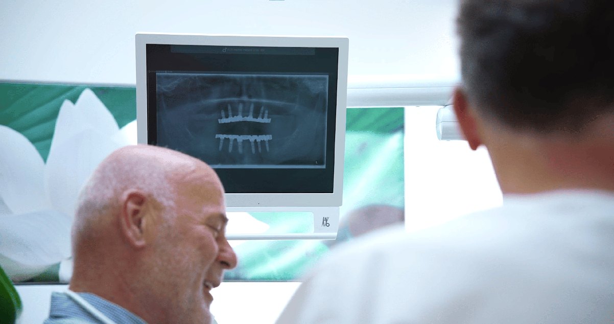 Patient vor dem Röntgenbild seiner Implantate